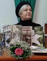 Halida Uzunović - mit schwarzer Mütze und heller Frisur sitzt sie vor mehreren Büchern. Vor den Büchern liegt ein Blumenstrauß mit einer rosa Rose.