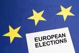 Ein Zettel mit der Aufschrift „European Elections“ liegt vor einer EU-Flagge mit drei gelben Sternen.