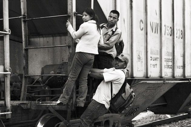 Migrant/innen aus Zentralamerika Drei Menschen halten sich an einem Eisenbahnwaggon fest