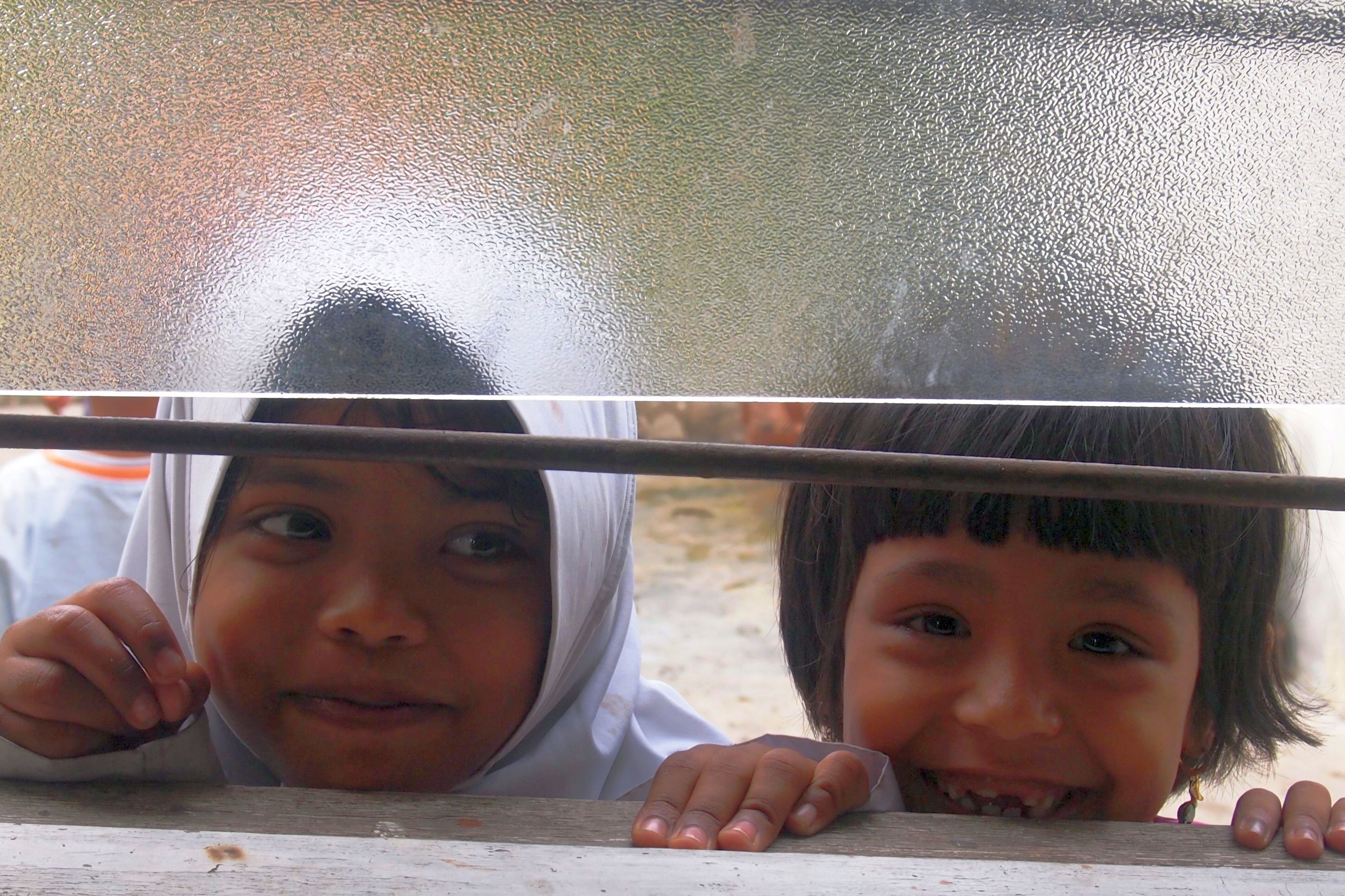 Geflüchtete Kinder in Malaysia Zwei Kinder schauen aus einem Fenster