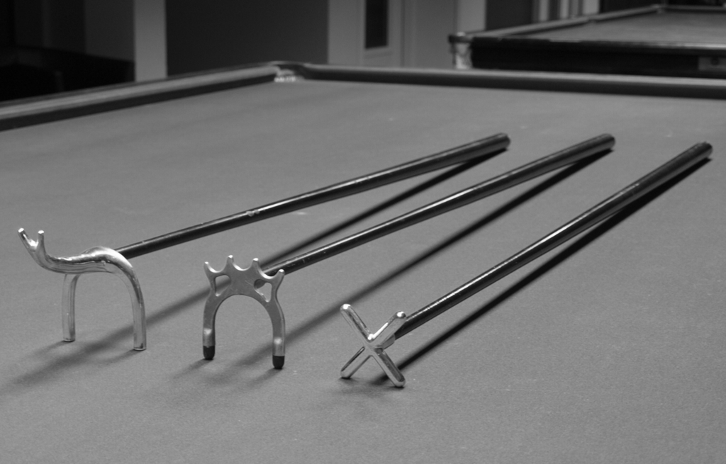 Drei verschiedene Hilfsqueues, die beim Snooker und Billard verwendet werden. Drei verschiedene Hilfsqueues auf einem Billardtisch