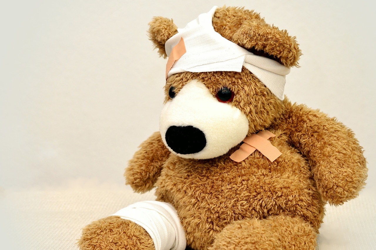 Kuscheltier mit Verbänden an Kopf und Arm Kuscheltier mit einem Verband an Kopf und Arm