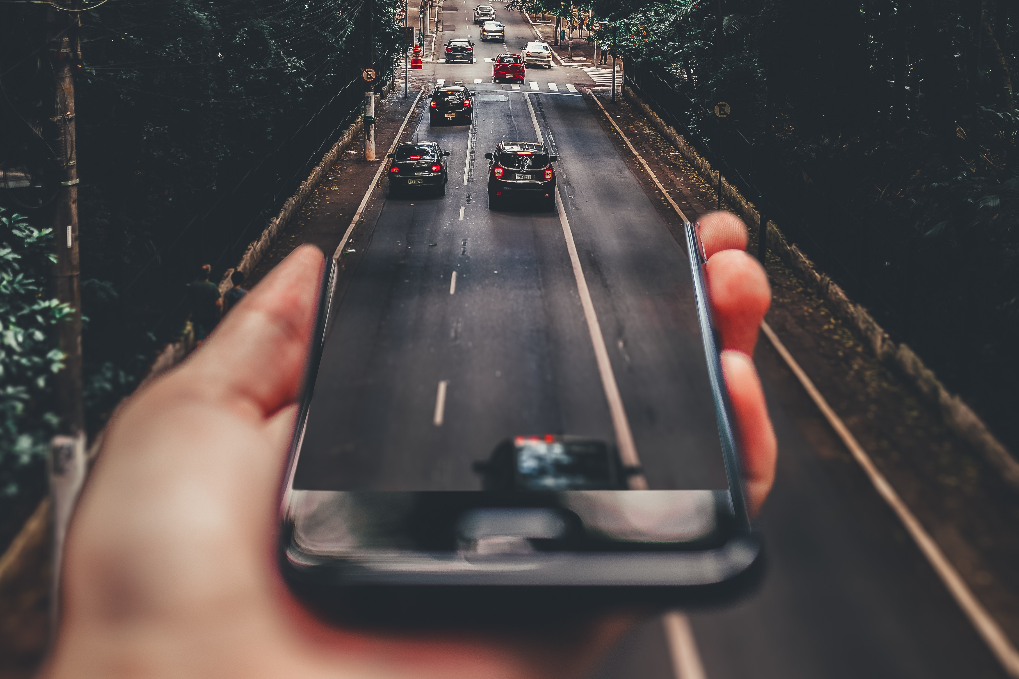Smart City für die kommunale Verkehrswende: Alle Verkehrsmittel aus einer Hand Kommunale Verkehrswende. Smart City. Eine Fotomontage aus einem Smartphone und Autobahn